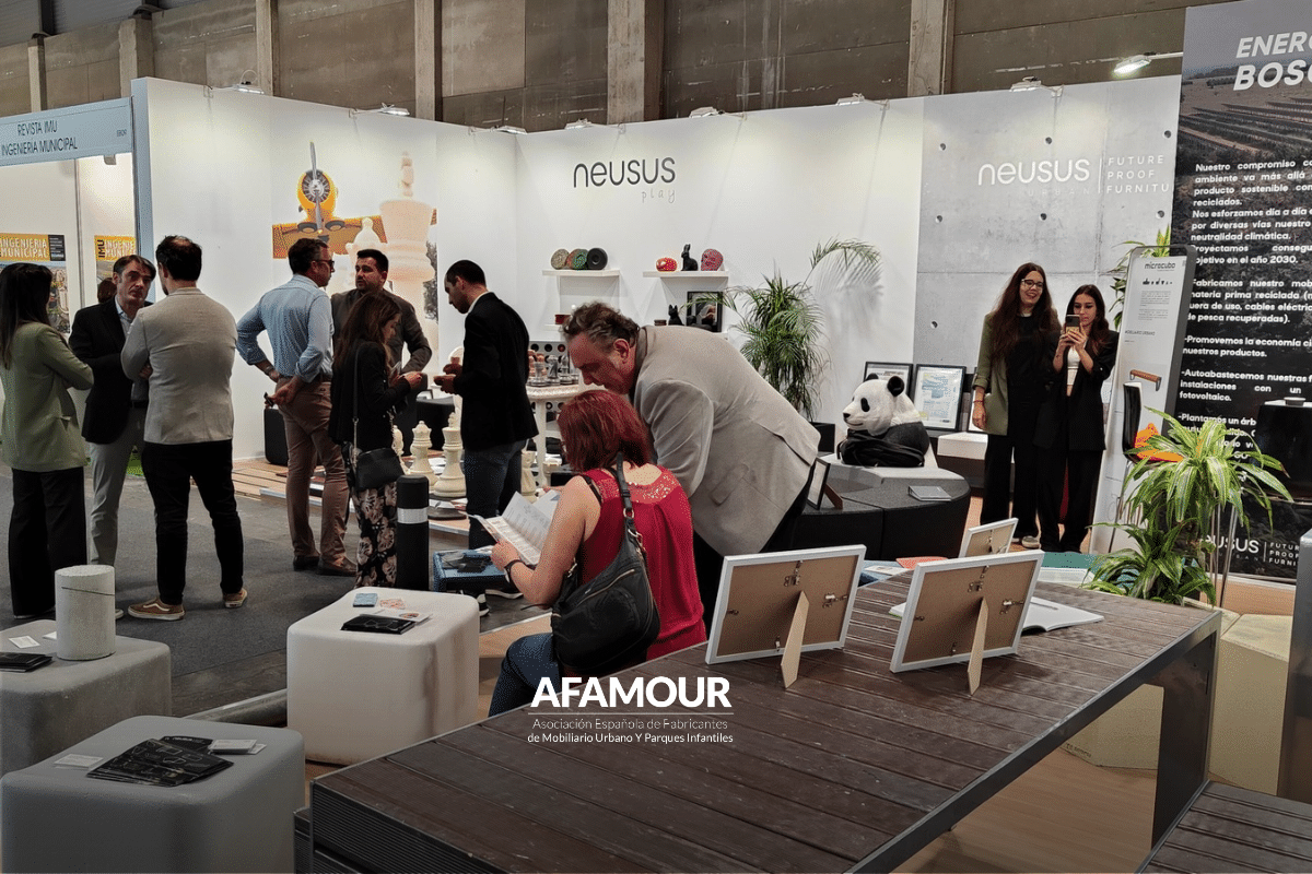 Vista general de un stand de mobiliario urbano en TECMA, con exposición de bancos, equipamientos y soluciones para espacios públicos y visitantes recorriendo la feria.