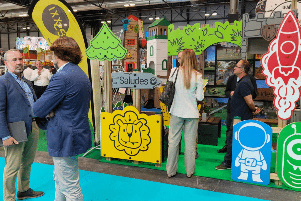 Profesionales visitando el stand de asociados de AFAMOUR en TECMA 2024, con paneles de juego, estructuras infantiles y soluciones para parques públicos.